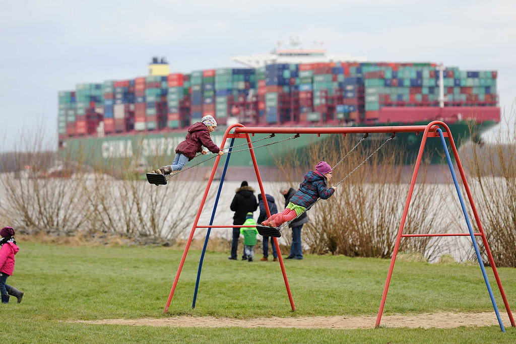 7674 Kinderspielplatz in Grnendeich an der Elbe - Kinder auf der Schaukel; im Hintergrund das havarierte Containerschiff CSCL Indian Ocean.