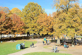 6646 Blick ber den Kinderspielplatz beim Planschbecken im Hamburger Stadtpark - hohe Bume mit bunt gefrbtem Herbstlaub sumen die Wege und den Platz; Kinder spielen in der Sonne. 