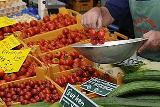 11_21542 Gemsestand auf dem Bergedorfer Wochenmarkt - frisches Vierlnder Gemse liegt in Kisten auf dem Verkaufsstand. Im Vordergrund Vierlnder Gurken, dahinter die leuchtend roten Vierlnder Tomaten.