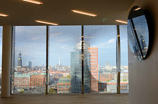 4978 Ausblick auf das Hamburg Panorama durch ein Fenster der Elbphilharmonie - im Vordergrund der Broturm am Kehrwieder + lks. der Kirchturm der St. Michaeliskirche ehem.? Wahrzeichen der Hansestadt Hamburg.