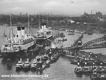 019_93788 | zwei Schiffe liegen an der berseebrcke im Hamburger Hafen; im Vordergrund eine Flotte von Schleppern + im Hintergrund die Kuppeln der St. Pauli Landungsbrcken.   