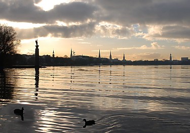 011_25895 | Hamburg Panorama an der Aussenalster; die Trme der Hansestadt ragen in den Abendhimmel; zwei Blesshhner auf dem Wasser.