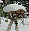 011_25886 | schneebedecktes Vogelhaus; Vgel nutzen die Winterftterung - Meisen fressen am Fett-Kndel und Nsse, whrend andere beim Fettfutter oder Sonnenblumenkerne sind.