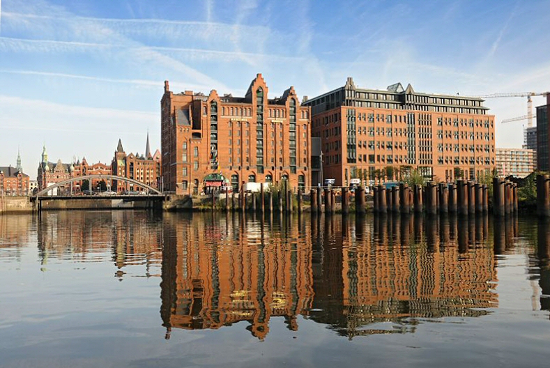 123_6103 | Die Backsteingebude der Hamburger Speicherstadt spiegeln sich im Wasser des Magedburger Hafens - in der Mitte der historische Hafenspeicher / Kaispeicher B. In diesem ehemaligen Hafenspeicher befindet sich das Internationale  Maritime Museum Hamburg; lks. davon die ehem. Magdeburger Brcke, die 2006 nach der sdkoreanischen Hafenstadt Busan neu benannt worden ist. Im Hintergrund die Giebeltrme der Speichergebude bei St. Annen. www.tuckerboot-hamburg.de Hamburg am Morgen - Maritimes Museum - Kaispeicher B - Wasserspiegelung im Magdeburger Hafen