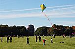 011_25985 | Kinder lassen auf der grossen Wiese im Stadtpark einen Drachen steigen; er hat eine Sonne aufgemalt und einen langen bunten Schwanz; im Hintergrund das Planetarium. 