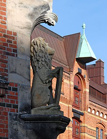 011_25999 | Hamburger Löwenskulptur am Lagerhaus; im Hintergrund eine Dachwinde mit Kranhaken in der Sonne.