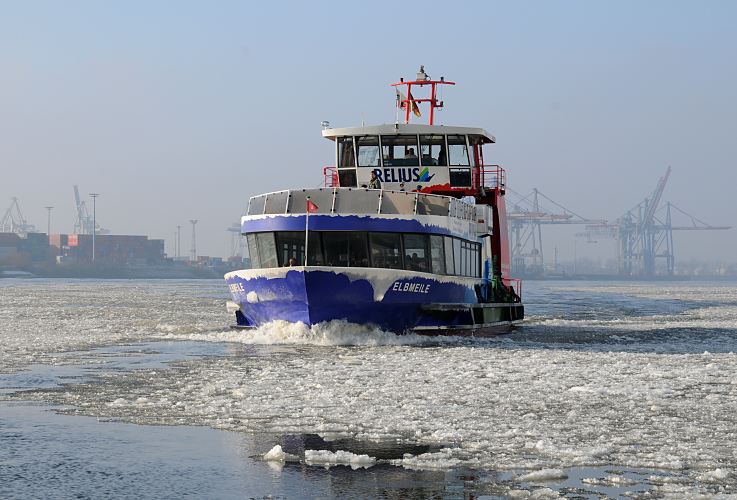 41_656542 |  Dichte Eisschollen treiben auf dem Wasser der Elbe - ein Fhre bahnt sich ihren Weg durch das Treibeis zum Anleger, um Fahrgste Richtung Landungsbrcken aufzunehmen. Das Fahrgastschiff der HADAG trgt den Namen ELBMEILE am Bug, der mit Eis bedeckt ist. Im Hintergrund am anderen Elbufer sind ein Containerlager und Krananlagen zu erkennen.  www.fotograf-hamburg.de 