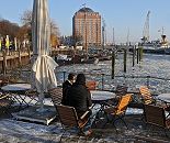 41_656544 |  Die Cafes am Elbufer in Hamburg Oevelgnne sind bei hufig auch im Winter geffnet - so ist es mglich in der Wintersonne am Museumshafen von Hamburg Oevelgoenne zu sitzen und auf das Eis der Elbe zu blicken. Im Hintergrund das ehemalige Khlhaus von Hamburg Neumhlen, in dem jetzt Senioren leben, die in der Lage sind ab ca. 2000 EUR monatlich zu zahlen.  www.fotograf-hamburg.de