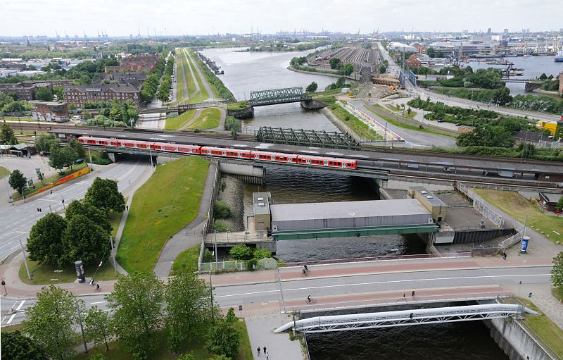 Fotografien aus den Hamburger Stadtteilen - Luftbild von der Veddel, Spreehafen, Hansahafen. Im Vordergrund hinter der Wilhelmsburger Brcke das Mggenburger Sperrwerk und die S-Bahnstation Veddel - ein roter S-Bahnzug steht an der Haltestelle. Die Backstein- Wohnhuser auf der linken Bildseite gehren noch zum Stadtteil Veddel, dahinter beginnt Hamburg-Wilhelmsburg. Der Spreehafen im Bildzentrum und der Hansahafen lks. sind Teil des Stadtteils Kleiner Grasbrook. www.fotograf- hamburg.de 