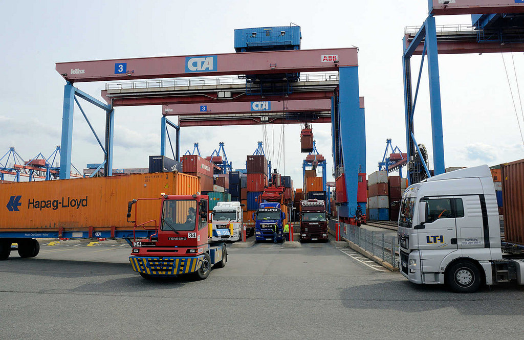 8874 Sattelschlepper / LKW am einem der Portalkrne auf dem Gelnde vom Hamburger Container Terminal Altenwerder. Einer der Metallboxen wird mit einem terminaleigenen Schlepper zum Containerbahnhof gebracht.