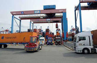 8874 Sattelschlepper / LKW am einem der Portalkrne auf dem Gelnde vom Hamburger Container Terminal Altenwerder. Einer der Metallboxen wird mit einem terminaleigenen Schlepper zum Containerbahnhof gebracht. 