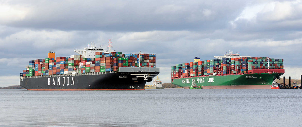 7788 Der Containerfrachter Hanjin Asia fährt auf der Elbe bei Stade - daneben die festgefahrene, havarierte CSCL Indian Ocean.