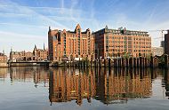 123_6103 | Die Backsteingebude der Hamburger Speicherstadt spiegeln sich im Wasser des Magedburger Hafens - in der Mitte der historische Hafenspeicher / Kaispeicher B. In diesem ehemaligen Hafenspeicher befindet sich das Internationale  Maritime Museum Hamburg; lks. davon die ehem. Magdeburger Brcke, die 2006 nach der sdkoreanischen Hafenstadt Busan neu benannt worden ist. Im Hintergrund die Giebeltrme der Speichergebude bei St. Annen. www.tuckerboot-hamburg.de