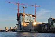 125_4652 | Hamburg am frhen Morgen - die aufgehende Sonne spiegelt sich in einem der modernen Brogebude am Kai des Grasbrookhafens. Hohe Baukrne stehen auf der Grobaustelle der Elbphilharmonie. Im Hintergrund die berseebrcke mit dem Museumsschiff Cap San Diego und die Hochhuser von Hamburg St. Pauli.