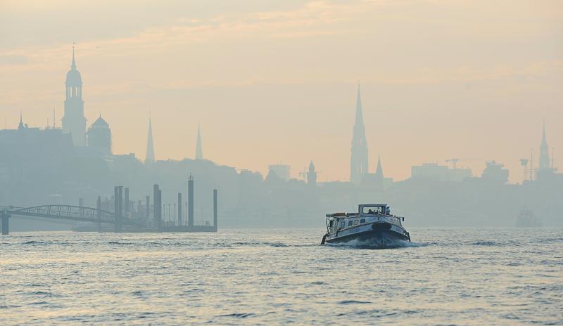 Hamburg am Morgen - Sonnenaufgang in Hamburg, Morgendunst - Hamburg Panorama.  27_3830 | Hamburg Panorama kurz vor Sonnenaufgang; das Hamburger Panorama mit den markanten Kirchtrmen sind im Morgendunst, der ber der Elbe liegt schon zu erkennen. Eine Barkasse bringt Hafenarbeiter an ihren Arbeitsplatz. 