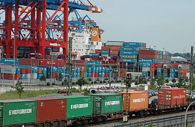 011_25843 | Arbeit im Hafen Hamburg; im Vordergrund transportiert ein Gterzug die Container aus dem Hafengebiet; im dahinter sind entladene Container gelagert - ein Frachtschiff liegt am Hafen Kai. 