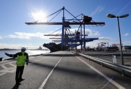 137_0079 | Ein HHLA Mitarbeiter gibt auf der Kaianlage des Container Terminal Altenwerder Anweisungen. Im Hintergrund Containerbrcken und das Containerfrachtschiff HYUNDAI FORCE. Beim hochautomatisierten Containerumschlag auf dem HHLA Container Terminal Altenwerder lschen und laden die mit zwei Katzen ausgestatten Containerbrcken an der Wasserseite die Stahlkisten vom bzw. auf das Schiff.