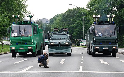 011_25937 | Fahrzeuge der Polizei haben am Millerntor in Hamburg St. Pauli Aufstellung genommen; ein Fotograf sitzt auf der Strasse und schiesst sein Bild.