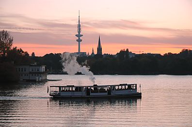 011_25947 | die St. Georg unter Dampf bei einer abendlichen Rundfahrt ber Hamburgs Alster und die Kanle - hier wendet das Schiff an der Bellevue - im Hintergrund der Fernsehturm und ein Kirchturm in der Abenddmmerung. 