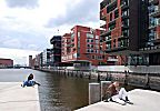 011_25976 | die neue Architektur der Hafencity; Blick von den Magellan Terrassen - Hamburg Touristen sitzen am Rand des Hafenbeckens vom Sandtorhafen. Im Hintergrund die Sandtorhafenklappbrcke und links der Kaispeicher A die zuknftigen Elbphilharmonie, dem neuen Wahrzeichen der Hansestadt Hamburg. 