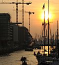 011_26039 |  Sonnenuntergang im Hamburger Hafen - die niedrig stehende Sonne scheint durch die Masten der historischen Segelschiffe im Hamburger Traditionsschiffhafen, der im Sandtorhafen erffnet wurde. Tuckerboote und Festmacher fahren Richtung Elbe, eine Barkasse liegt unter Dampf, der in das Abendrot vom Hamburger Himmel steigt. Lks. die Baustelle Am Kaiserkai in der Hafencity, im Hintergrund Baukrne am Kaispeicher A, wo die Hamburger Elbphilharmonie entstehen soll.   www.christoph-bellin.de 