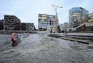 890_0955 Eine Sturmflut hat Teile der Marco-Polo-Terrassen in dem Hamburger Stadtteil Hafencity unter Wasser gesetzt - ein Rettungsring am Gelnder der Terrassen wird vom Wasser umsplt. Die Kaimauern des Grasbrookhafens sind nicht mehr zu erkennen. Passanten stehen an den Terrassen und beobachten das Geschehen - im Hintergrund Brohuser mit erleuchteten Fenstern. Hochwasser in der Hamburger Hafencity - Marco Polo Terrassen unter Wasser. 