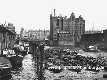 019_93799 | Blick in den Magdeburger Hafen; Schuten mit Kohle beladen und Binnenschiffe liegen am Kai - re. der Kaispeicher B und im Hintergrund die Kontor- und Lagerhuser der Speicherstadt.