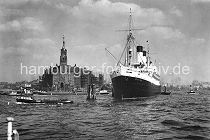 172_0276 Der Passagierdampfer Monte Rosa hat an den Holzdalben in der Elbe fest gemacht. Das Schiff lief 1930 vom Stapel und wurde auf der Hamburger Werft Blohm & Vo gebaut. Eine Barkasse mit Hafenarbeitern fhrt Richtung Baumwall und ein Binnenschiff biegt in Sandtorhafen ein, dessen Hafenbecken links im Hintergrund zu erkennen ist. Auf dem Uhrturm des 1876 erbauten Kaiserspeichers /  Kaispeichers ist die Zeitballanlage zu erkennen, die von der Sternwarte am Millerntor ausgelst wurde. Der Ball hatte einen Durchmesser von einem Meter und wurde exakt Mittags um 12.00 Uhr weit sichtbar fallen gelassen.